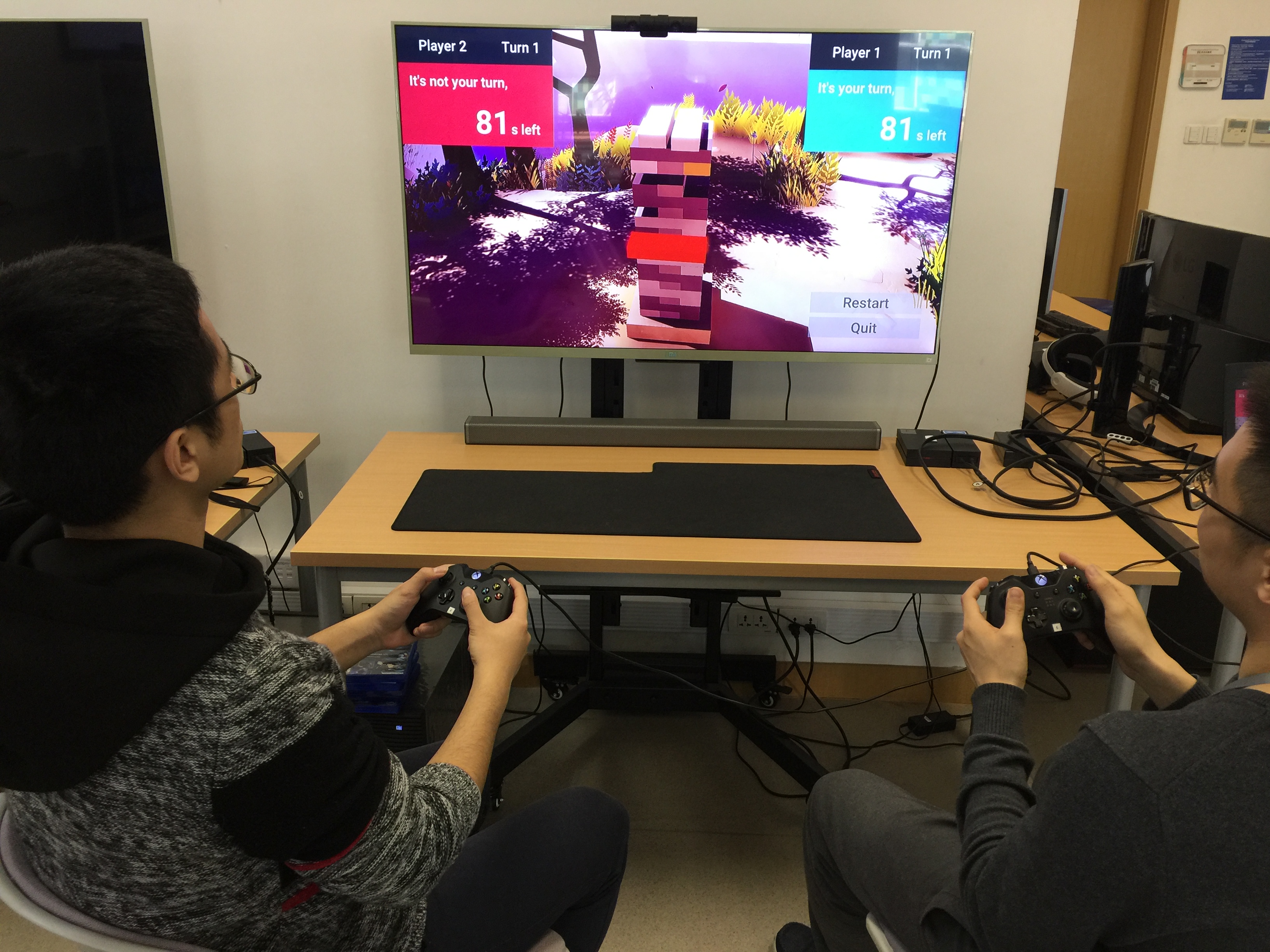 Image of 2 co-located players playing blocktower on a shared large tv display.